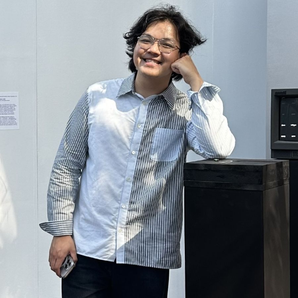 Portrait of Ivan Zhao leading against a plinth in an art installation.